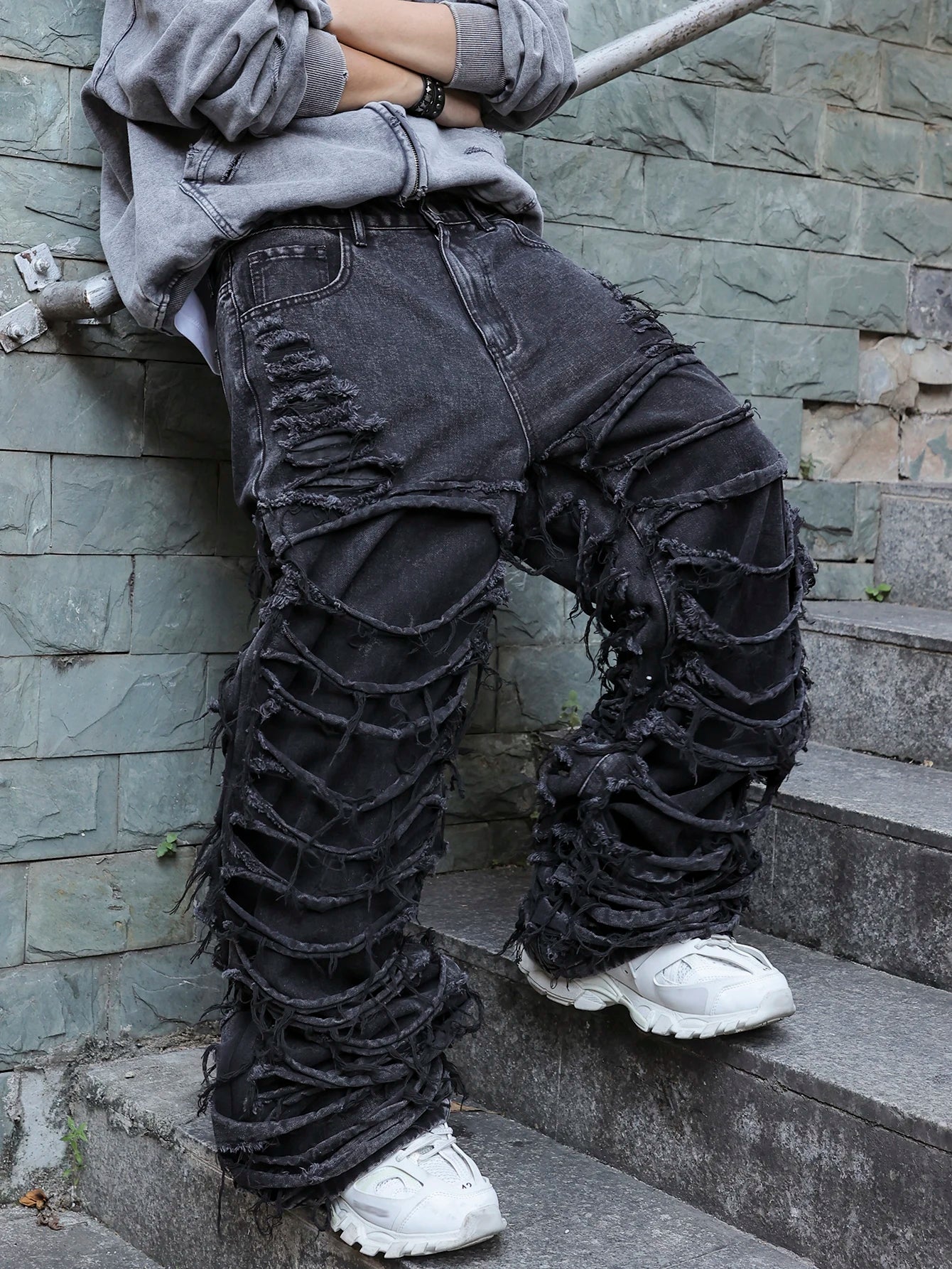 Men's black jeans. With a design of (ripped holes) and tassels. In a street trend style.